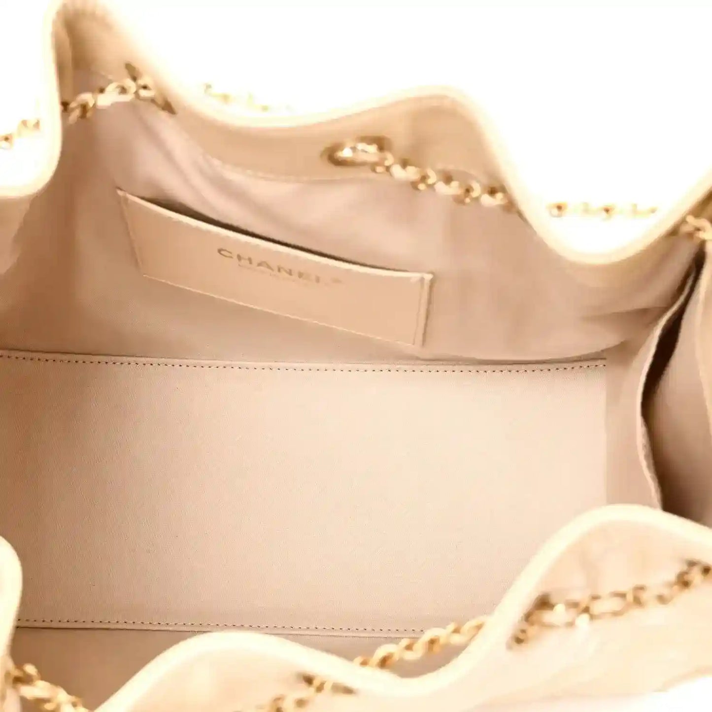 Light beige handbag interior with Chanel logo label and gold-tone chain detail