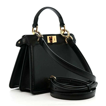 Black leather structured satchel with top handles, gold hardware, and crossbody strap
