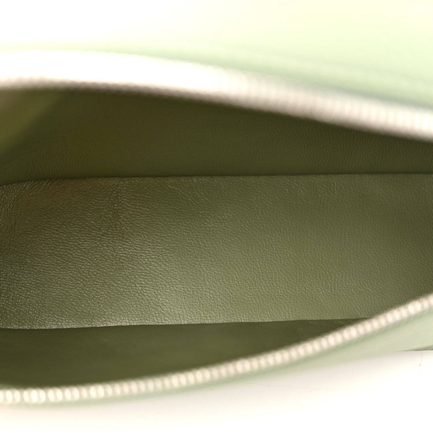 Sage green leather pouch interior with top zipper edge visible