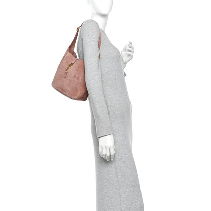 Small suede hobo bag, barley pink, held by top handle with side profile view