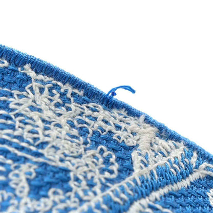 Blue and cream embroidered tote bag corner with fringe trim, close-up