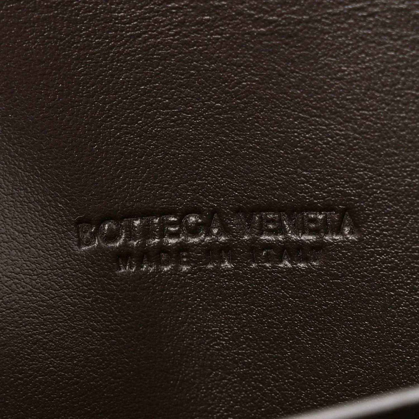Bottega Veneta embossed leather clutch exterior in dark tone