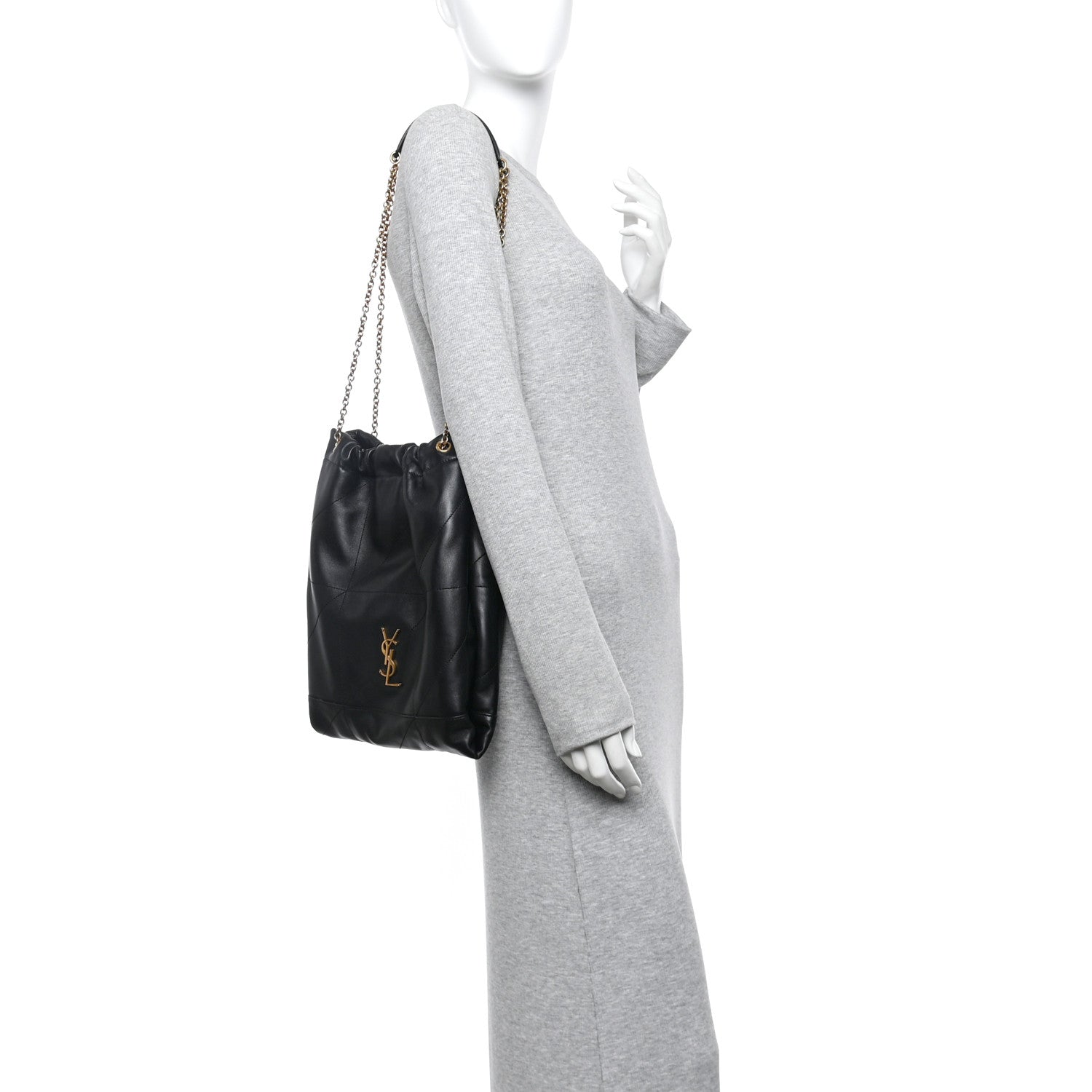 Black quilted leather drawstring bag with gold chain worn alongside gray sleeve