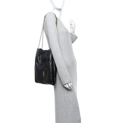 Black quilted leather drawstring bag with gold chain worn alongside gray sleeve