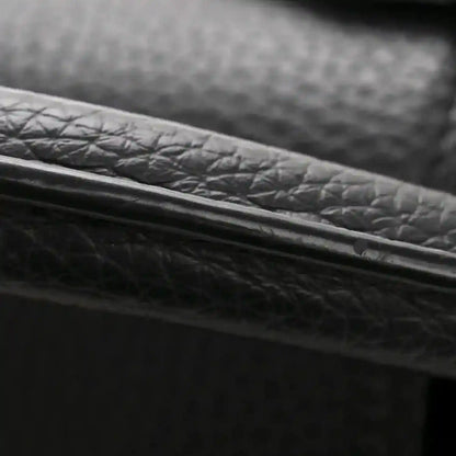 Black textured leather bag edge with gold-toned trim close-up