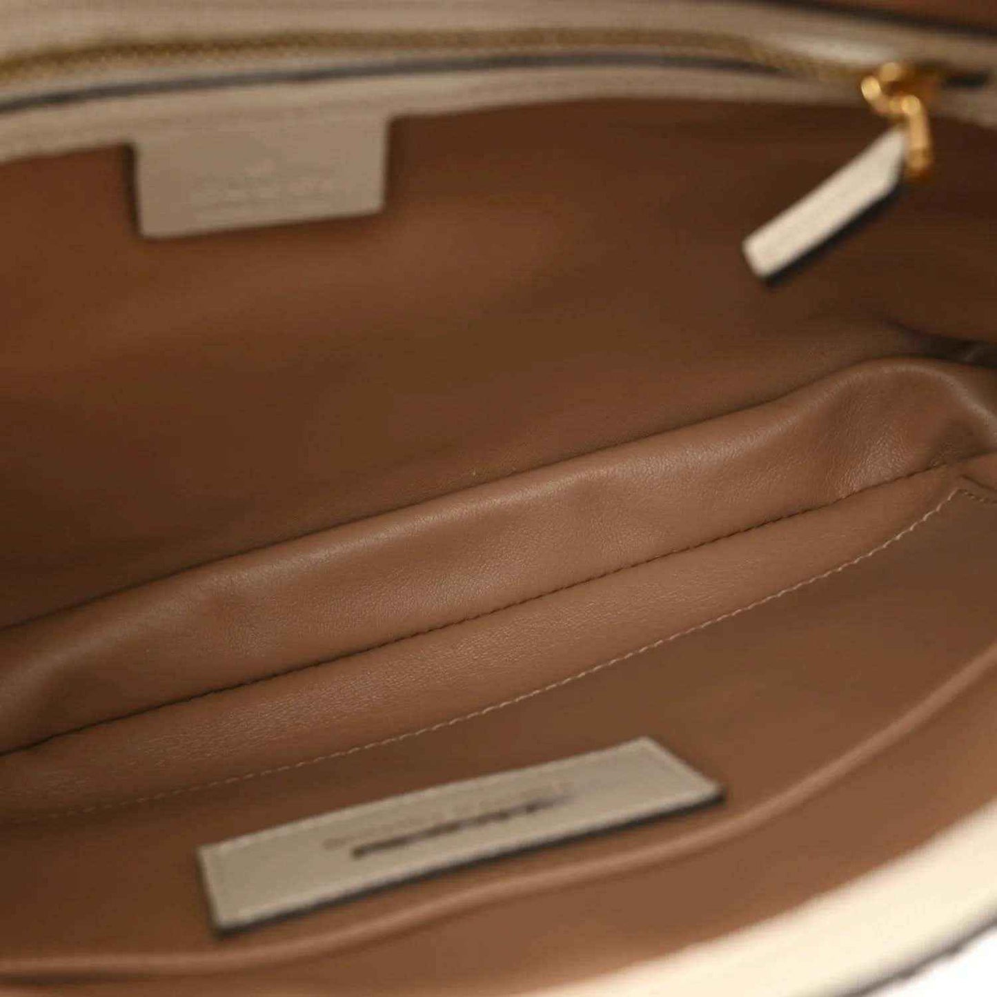 Hobo bag interior with brown lining, stitched seam, and metal interior tag.