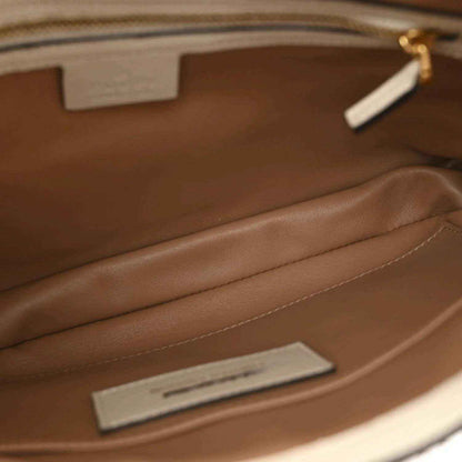 Hobo bag interior with brown lining, stitched seam, and metal interior tag.