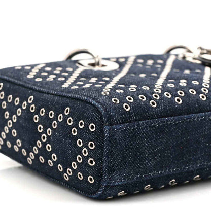 Dark blue denim handbag side corner with silver-tone eyelet dots and top stitching