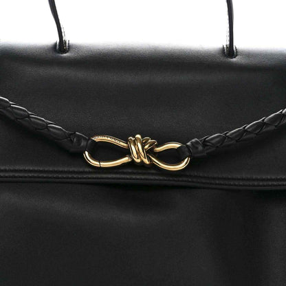 Black leather Ciao Ciao shoulder bag front clasp detail with braided cords and gold hardware.