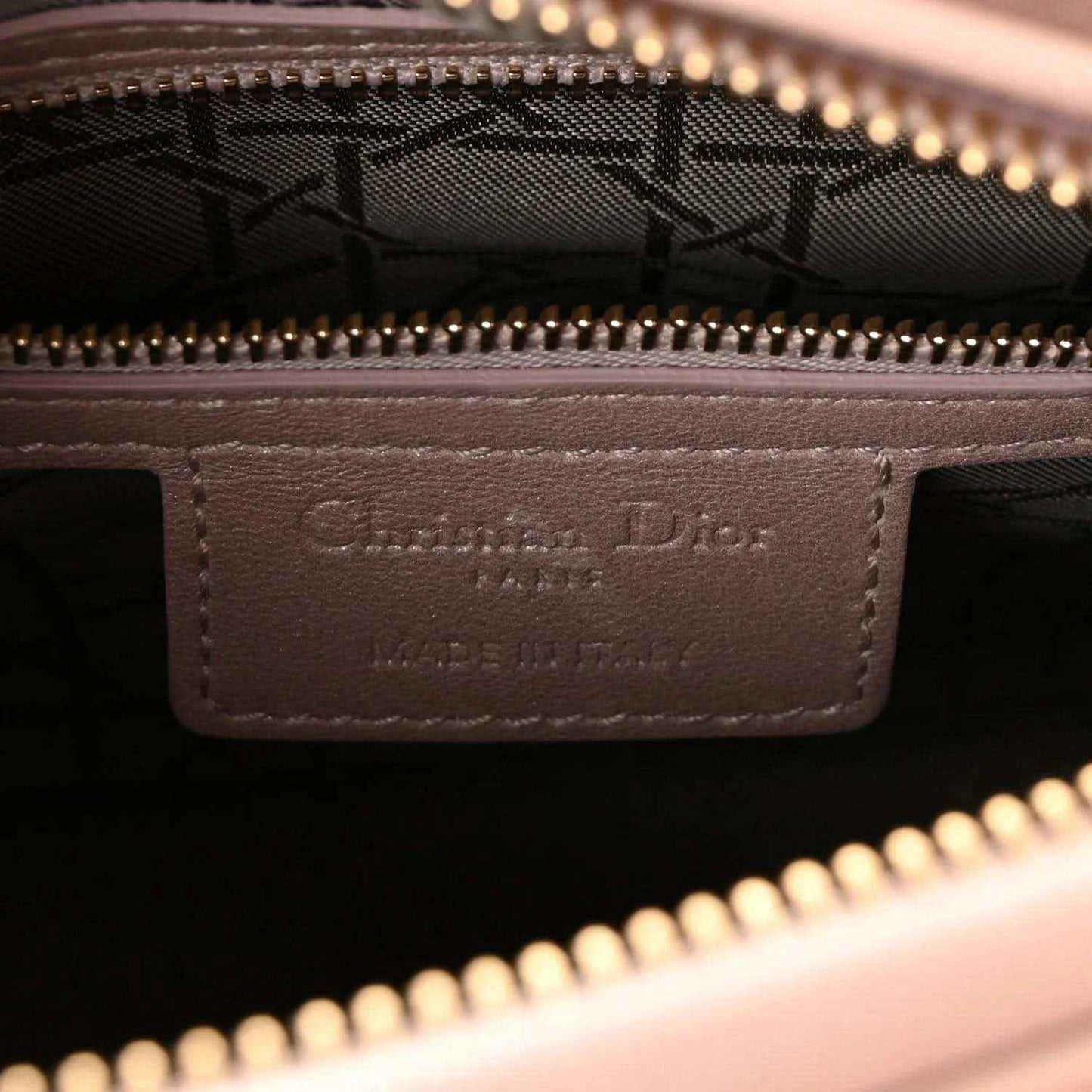 Handbag interior leather label with embossed branding under gold zipper trim