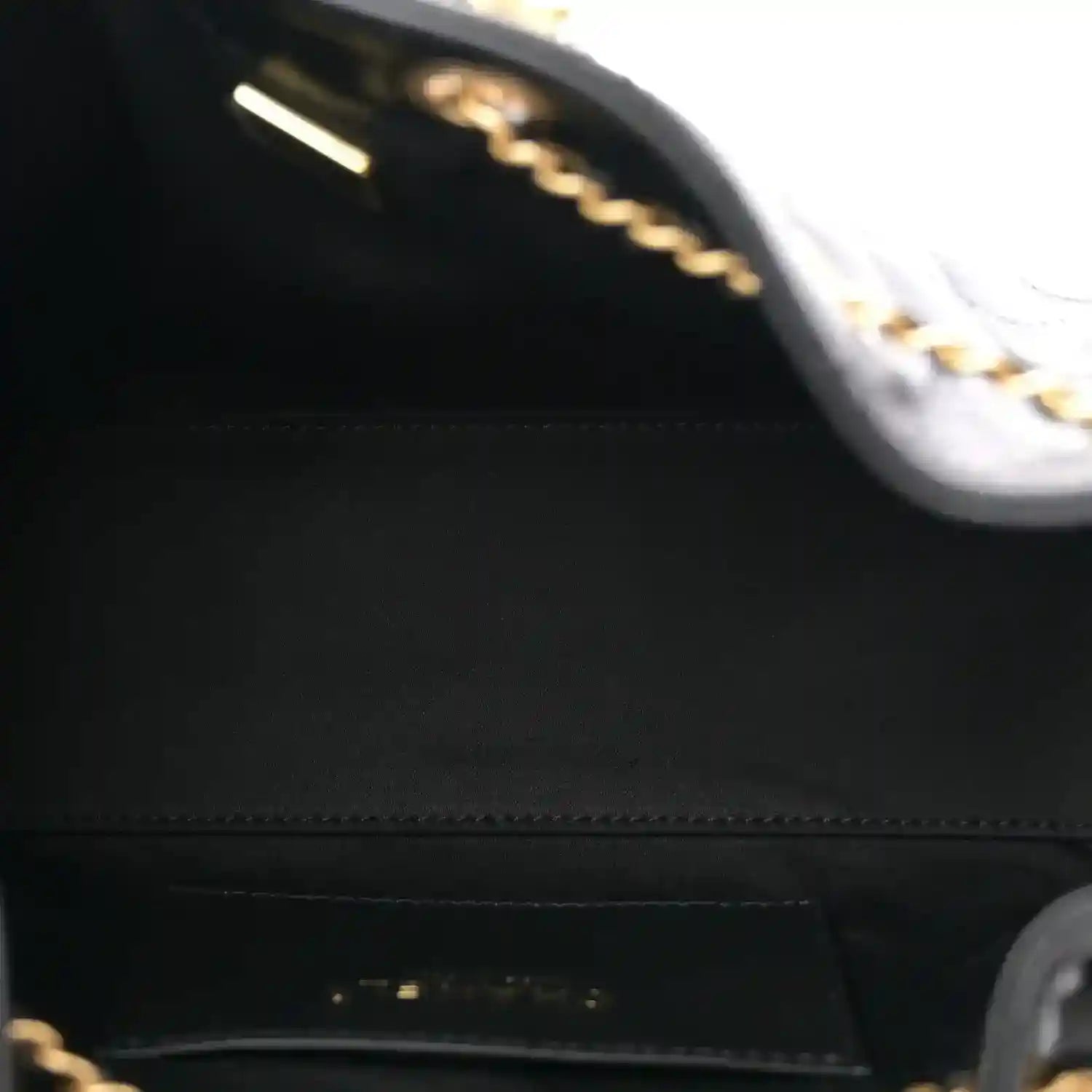 Black leather handbag interior with stitched edge and chain detail