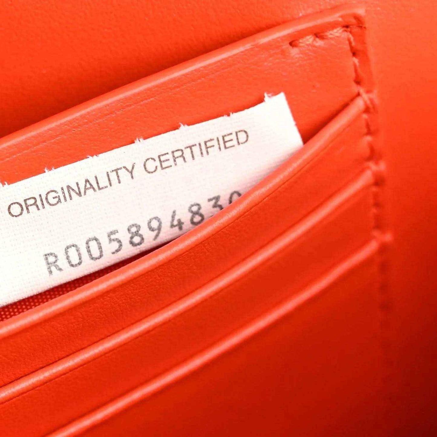 Orange nappa clutch interior with "ORIGINALITY CERTIFIED" tag and number