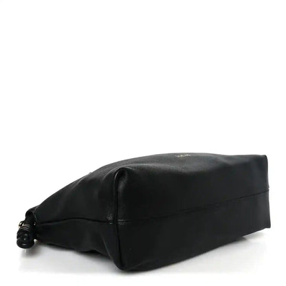Black leather clutch bottom view with rounded corners and small twisted drawcord detail.