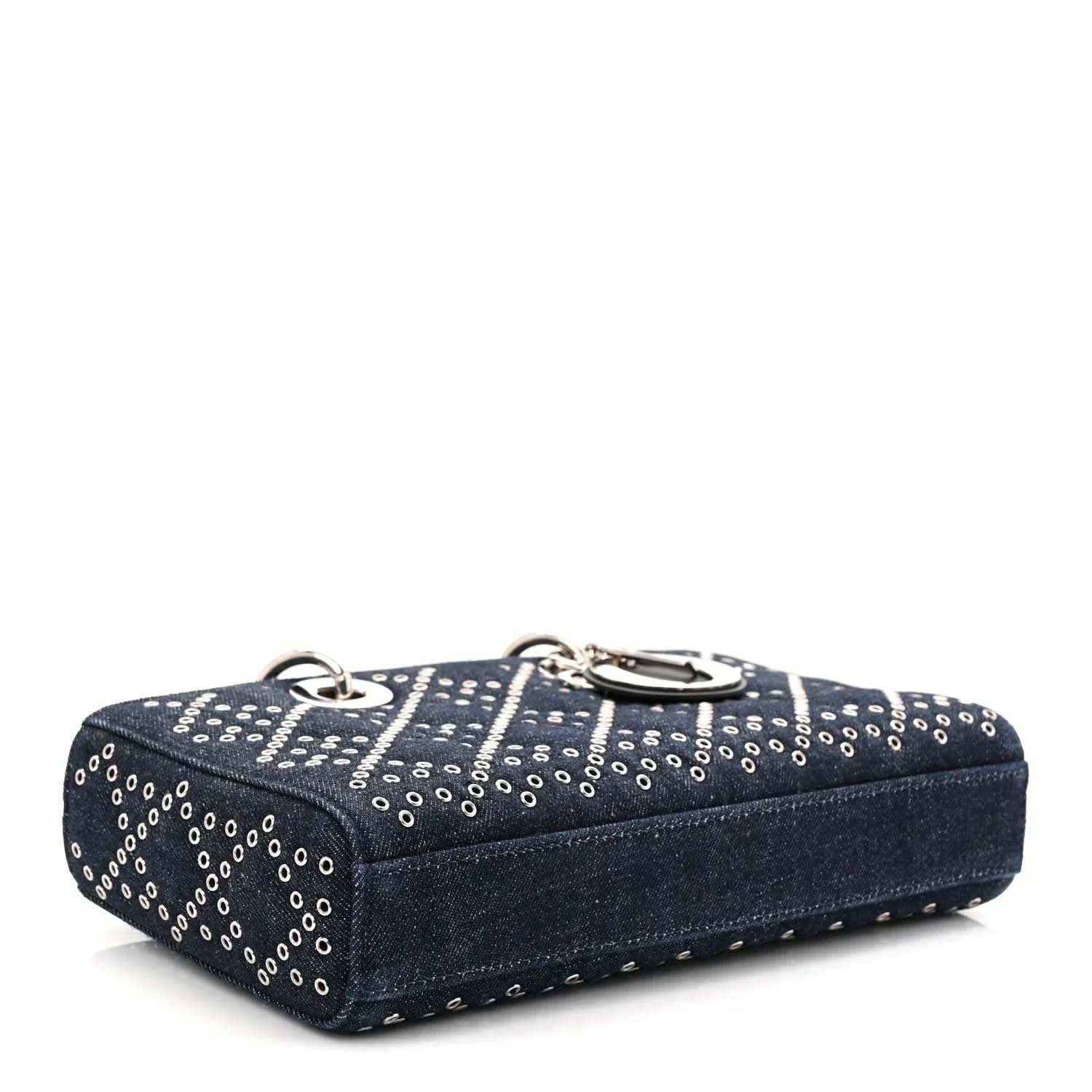 Denim eyelet handbag in dark blue with silver-tone rings, top handle, and stitched edges