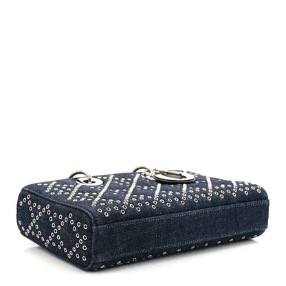 Denim eyelet handbag in dark blue with silver-tone rings, top handle, and stitched edges