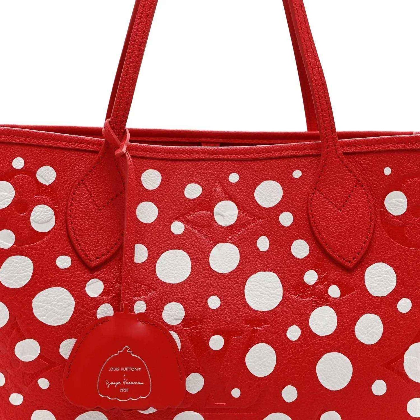 Red polka-dot tote bag close-up with top handles and central leather emblem