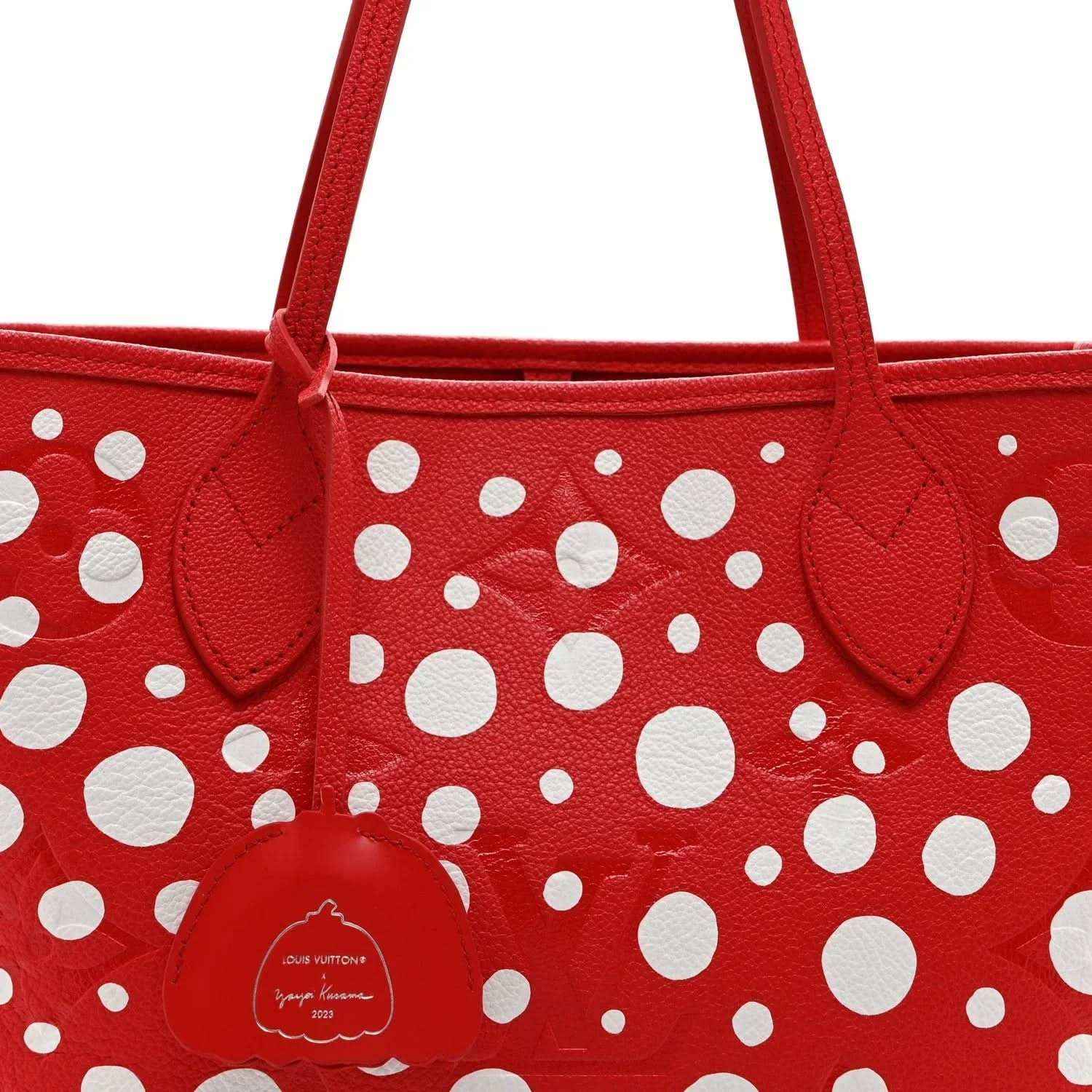 Red polka-dot tote bag close-up with top handles and central leather emblem