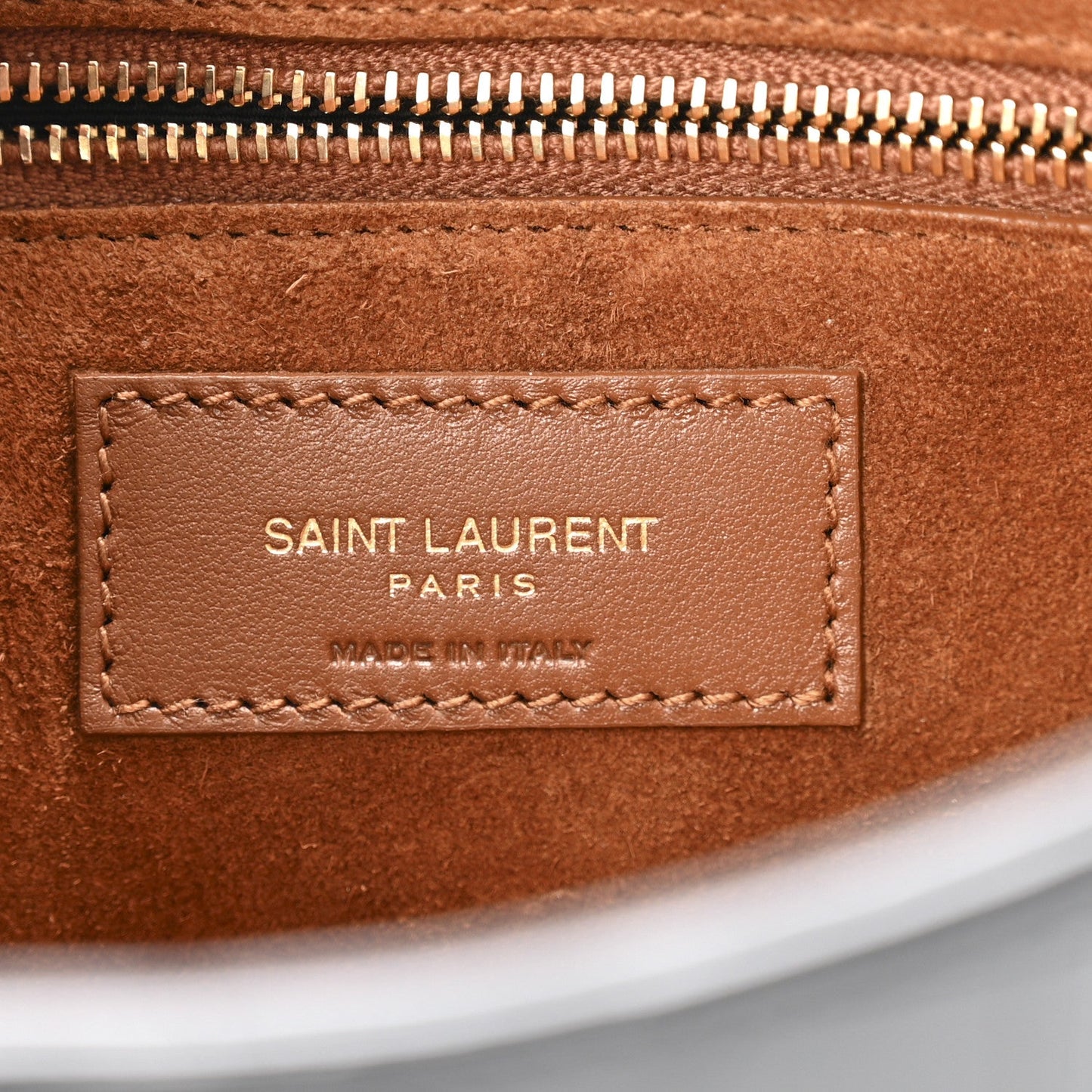 Close-up of tan leather label inside hobo bag with zipper teeth.