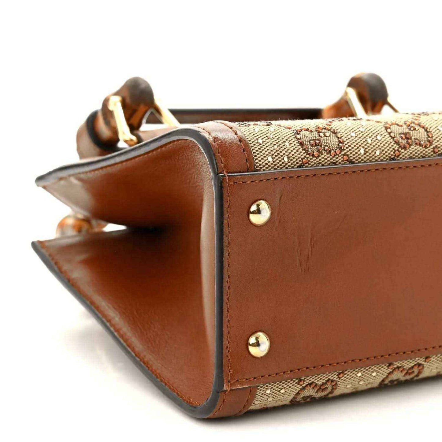 Gucci mini tote bag side corner with brown leather edges and gold-tone studs.