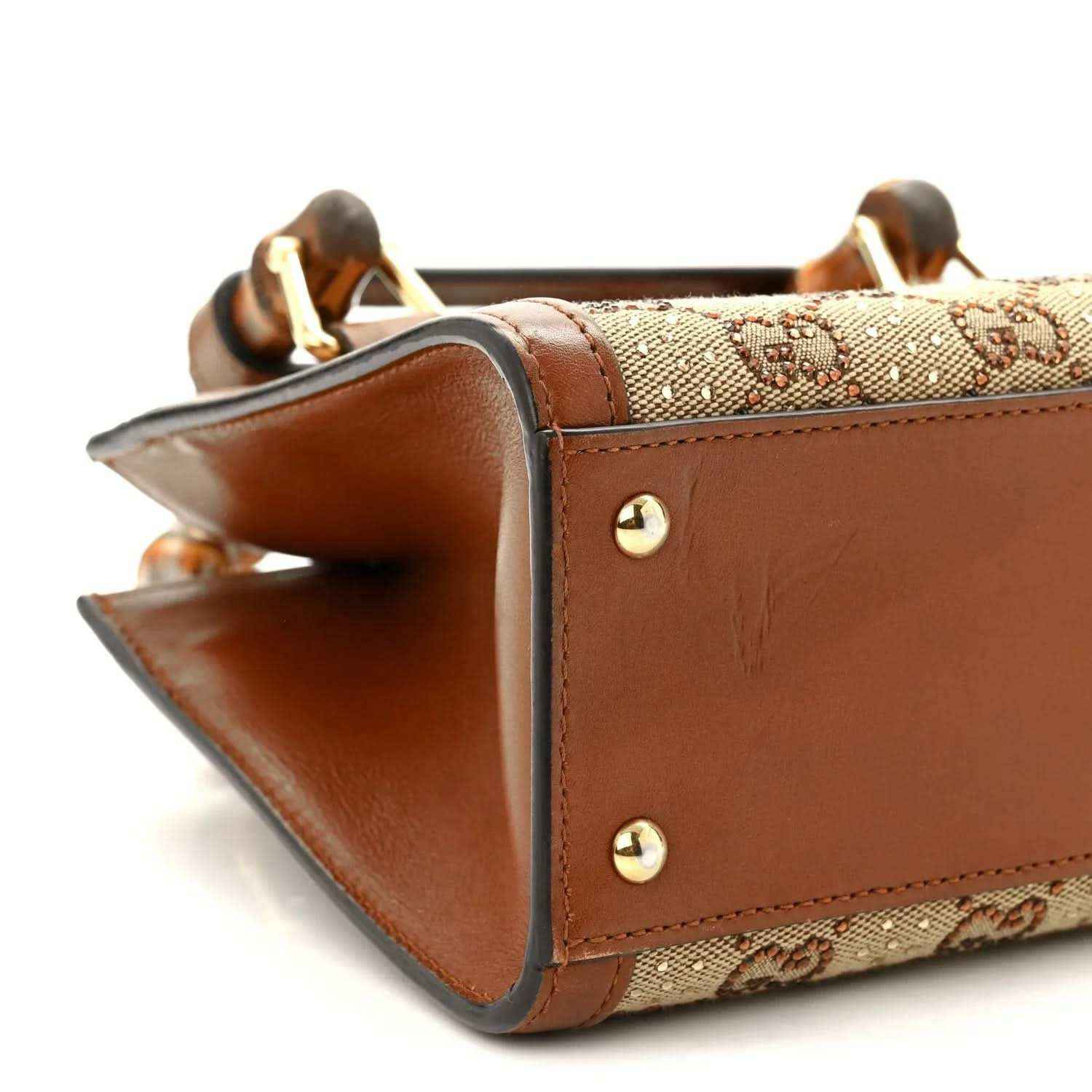 Gucci mini tote bag side corner with brown leather edges and gold-tone studs.