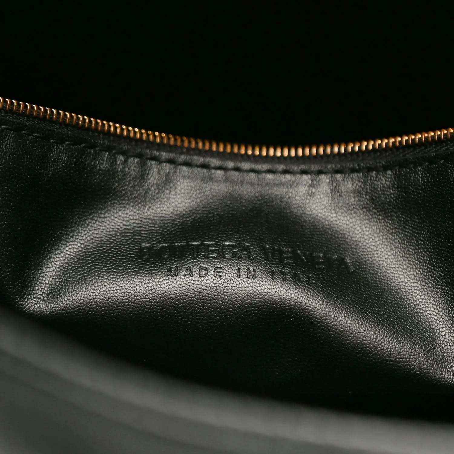 Black leather bag interior with gold-tone zipper and subtle embossed branding