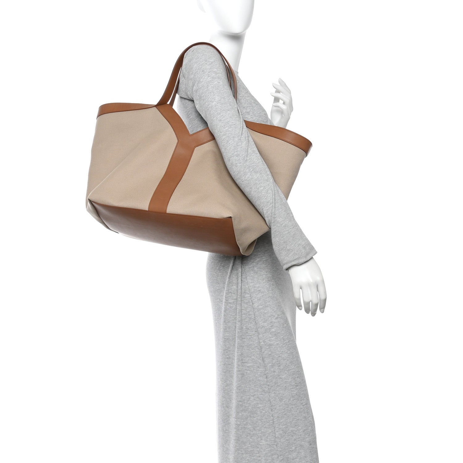 Tan tote with brown leather trim, held by model with gray sleeve