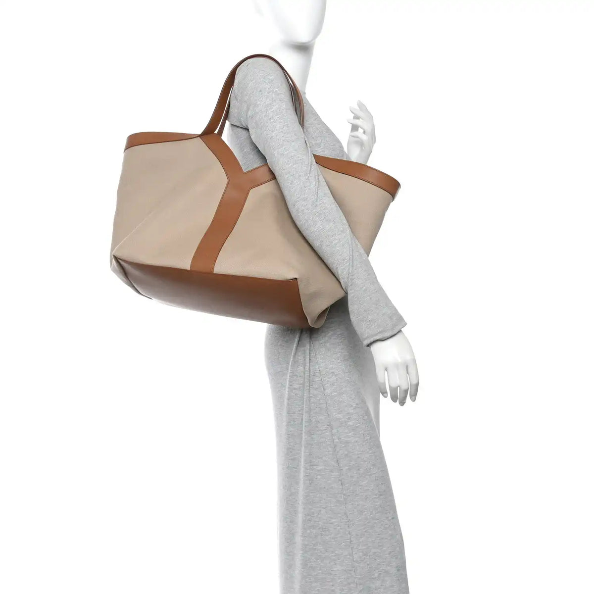Tan tote with brown leather trim, held by model with gray sleeve