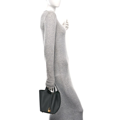 Dark green leather mini tote worn on shoulder with gold-tone lock detail
