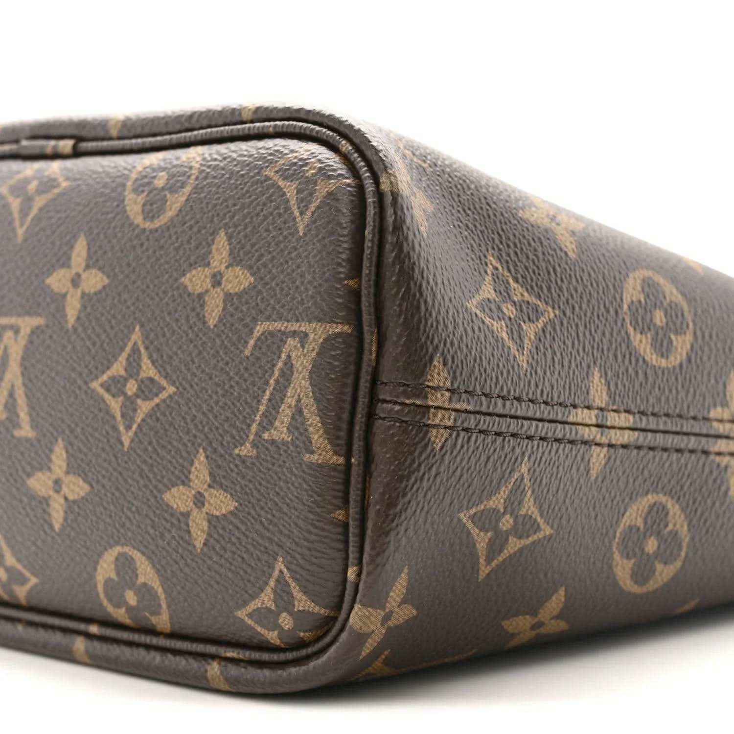 Monogram pouch corner close-up with black trim, stitched seams, and brown patterned canvas