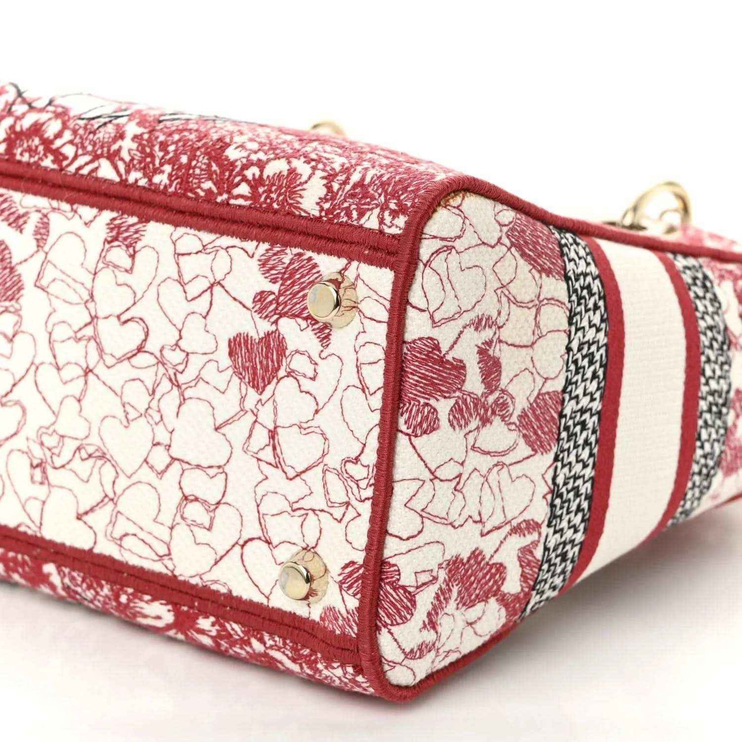 Embroidered canvas bag end panel in red-and-white heart pattern with gold studs.