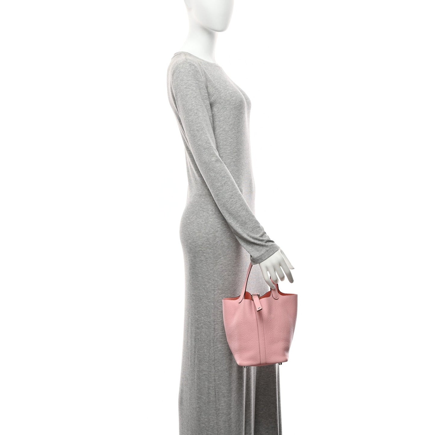 Pink textured leather handbag worn at side with top handles and padlock closure