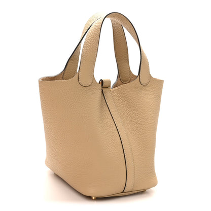Beige leather tote bag with side panel seam and gold lock closure hardware