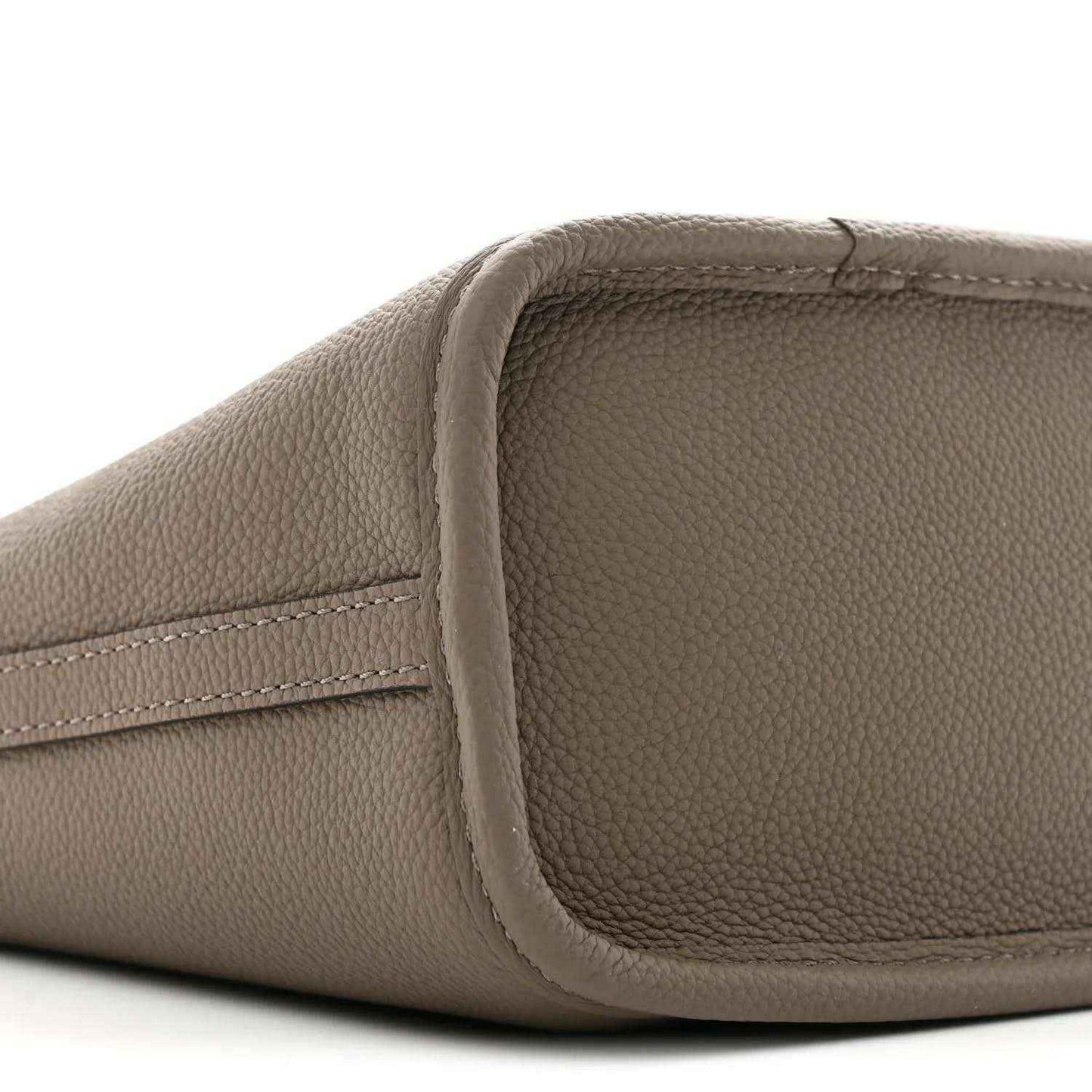 Gray pebbled leather side panel with stitched edge on a monogram bag