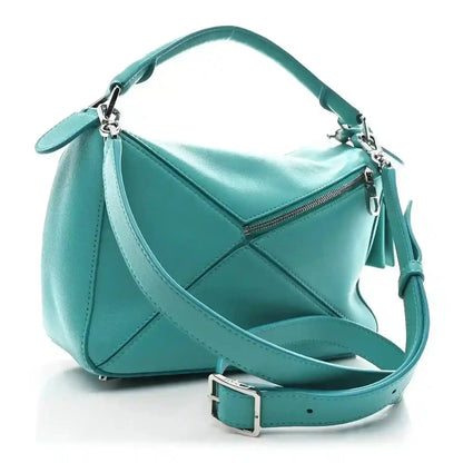 Small Puzzle bag in teal-blue leather with zip top and crossbody strap; side angle.