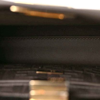 Dark brown leather satchel close-up with stitched seam detail.