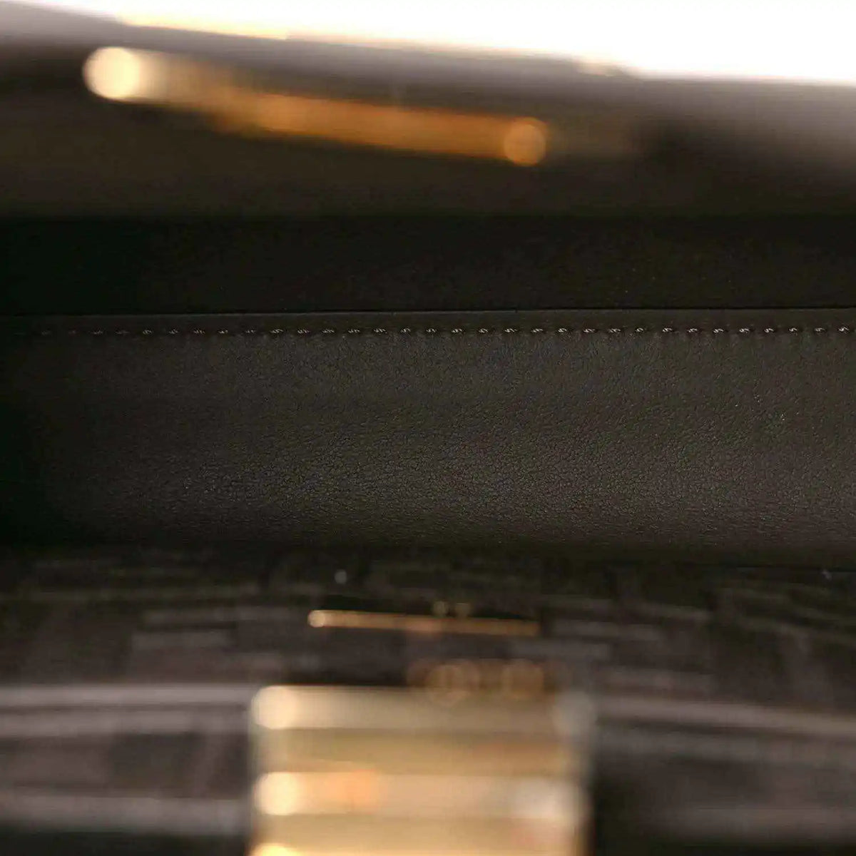 Dark brown leather satchel close-up with stitched seam detail.