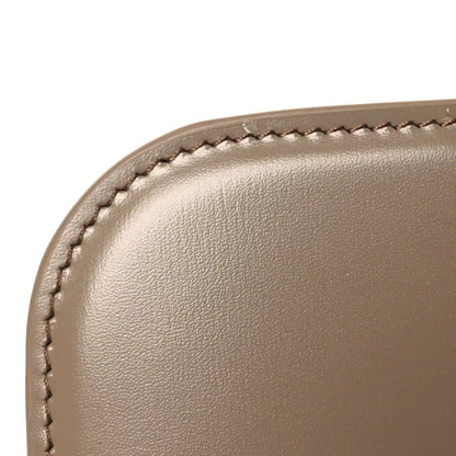 Shiny brown leather bag corner close-up with stitched edge and smooth grain