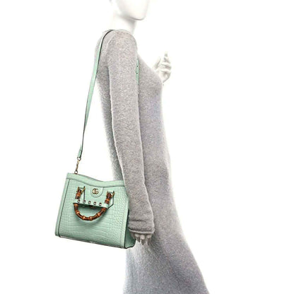 Green small tote bag worn on shoulder with thin crossbody strap and gold-tone hardware