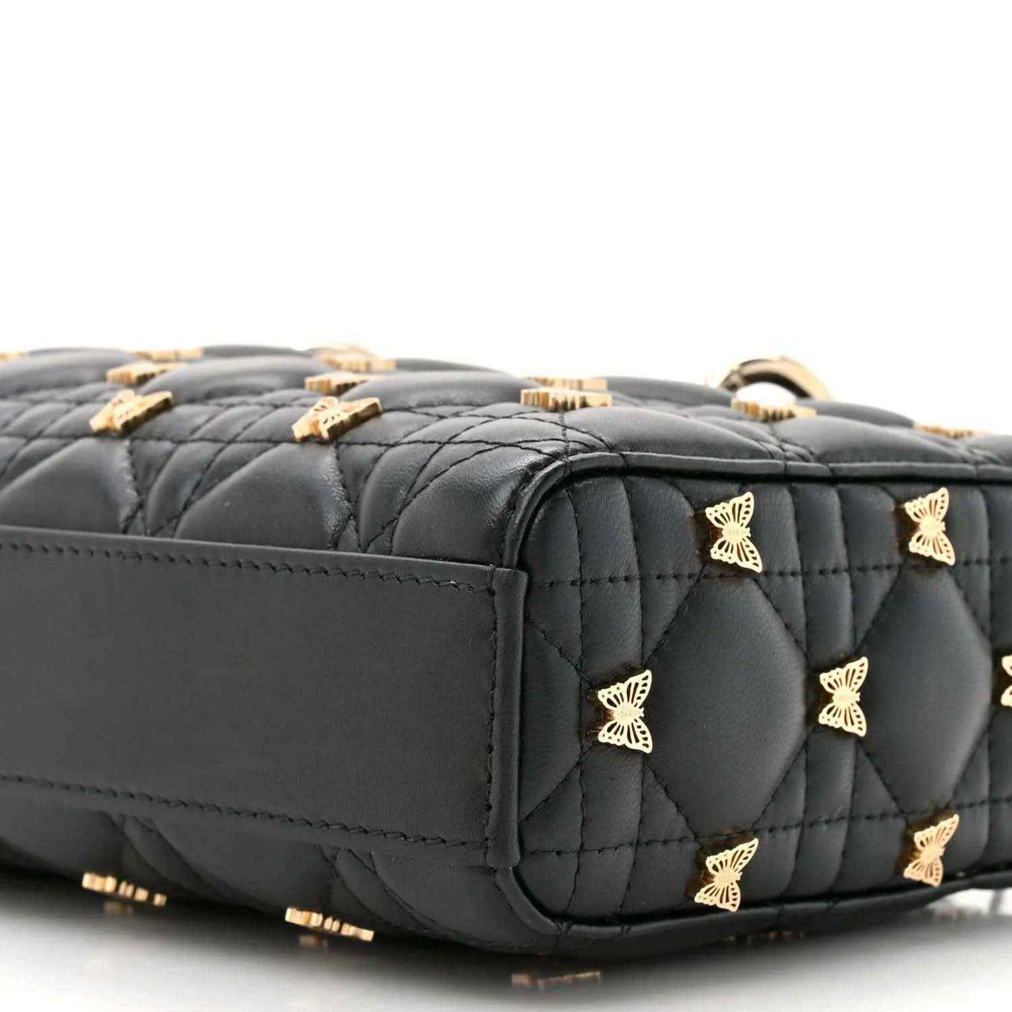 Black quilted top handle bag with scattered butterfly motifs and gold-tone trim, close-up