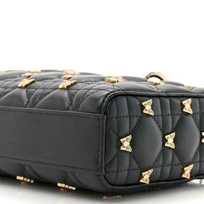 Black quilted top handle bag with scattered butterfly motifs and gold-tone trim, close-up