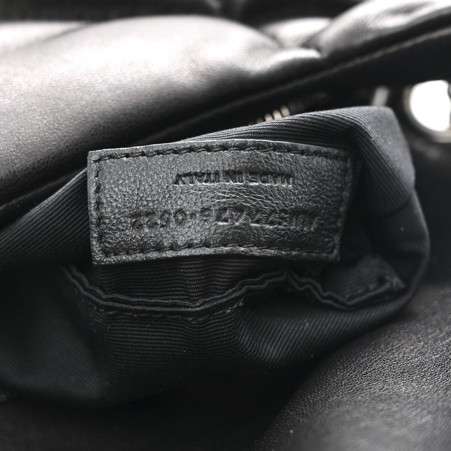 Black leather brand label inside quilted puffer satchel with fabric lining edges.