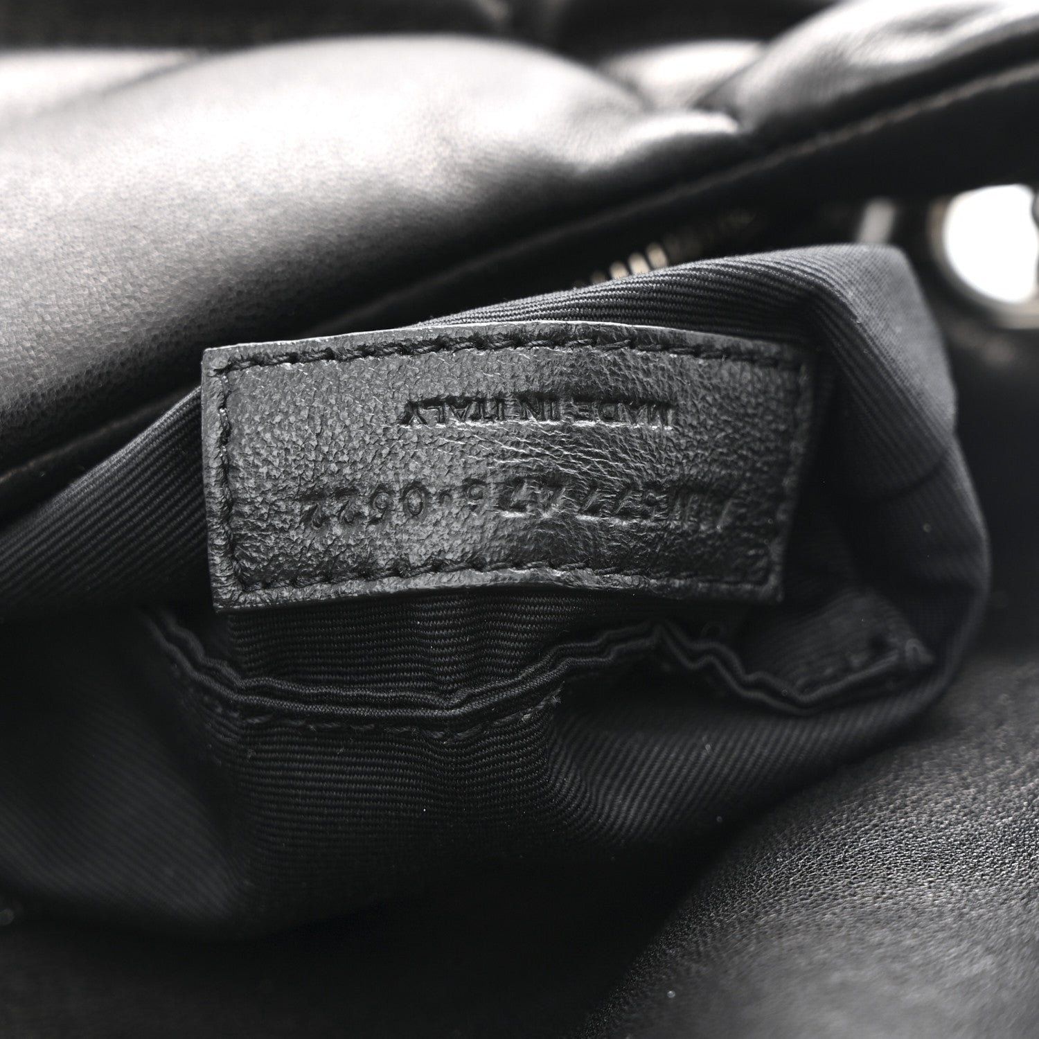 Black leather brand label inside quilted puffer satchel with fabric lining edges.