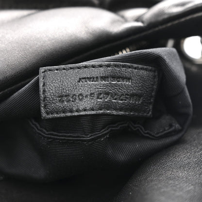 Black leather brand label inside quilted puffer satchel with fabric lining edges.