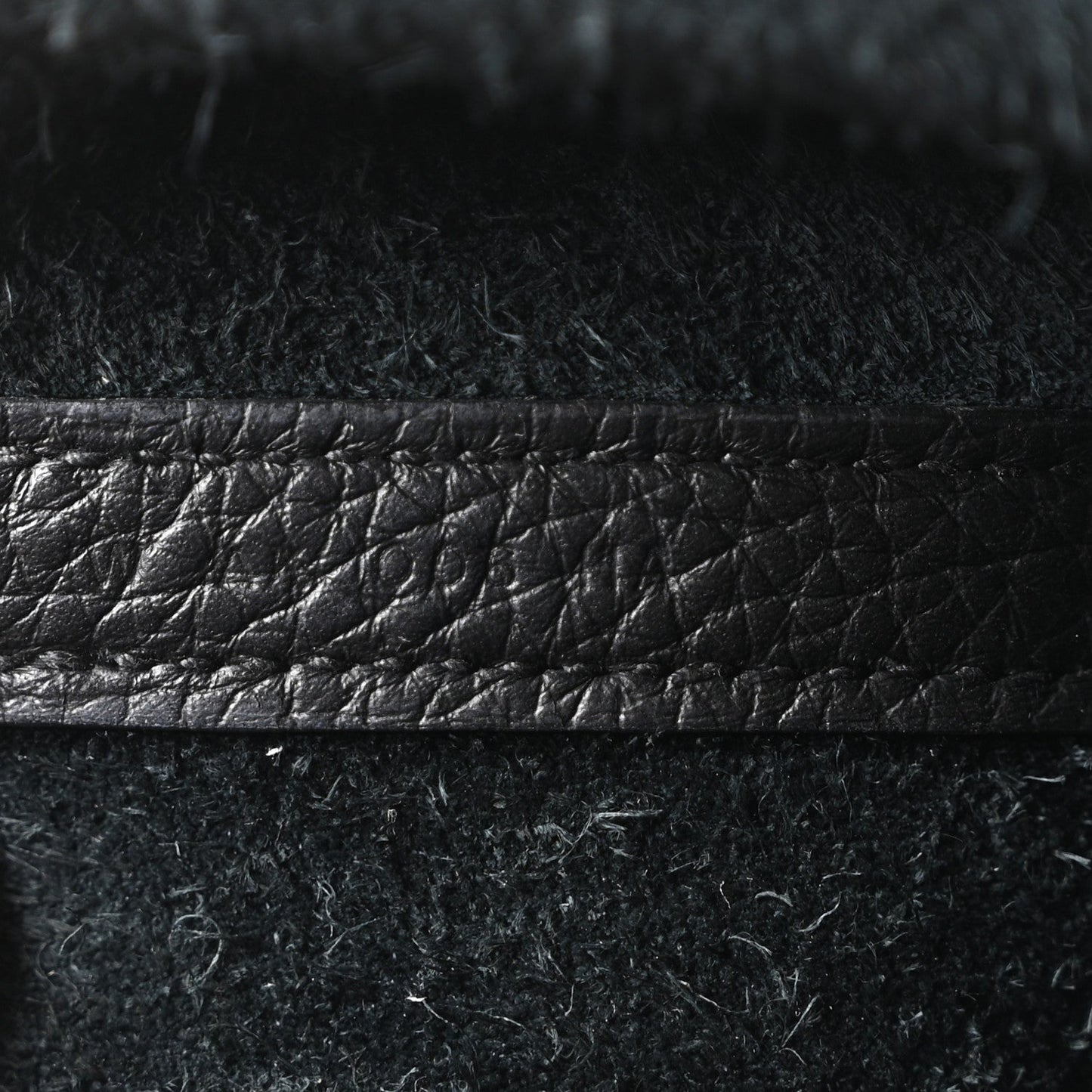 Black leather tote bag close-up of textured finish and stitched horizontal edge