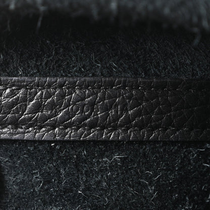 Black leather tote bag close-up of textured finish and stitched horizontal edge