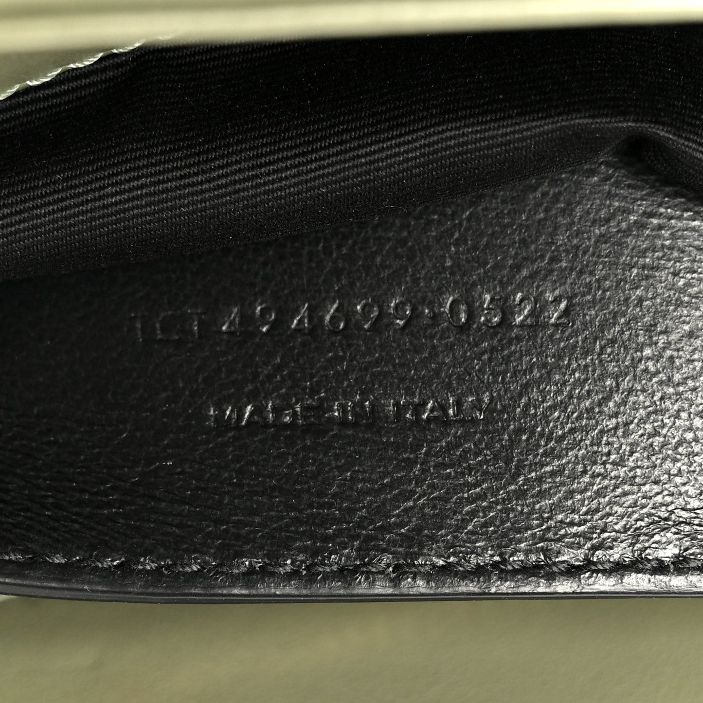Light sage leather interior base with stamped serial text near zipper opening
