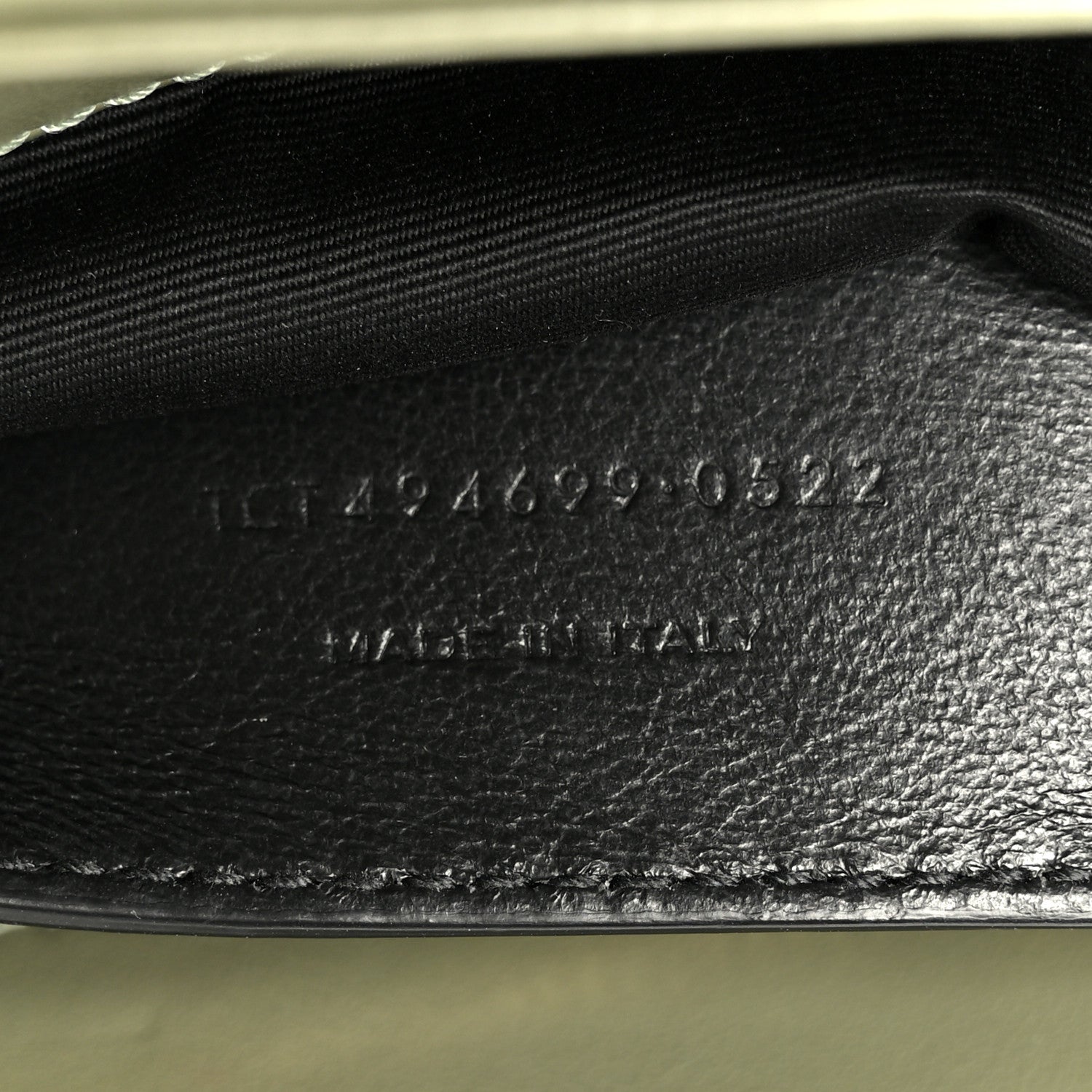 Light sage leather interior base with stamped serial text near zipper opening
