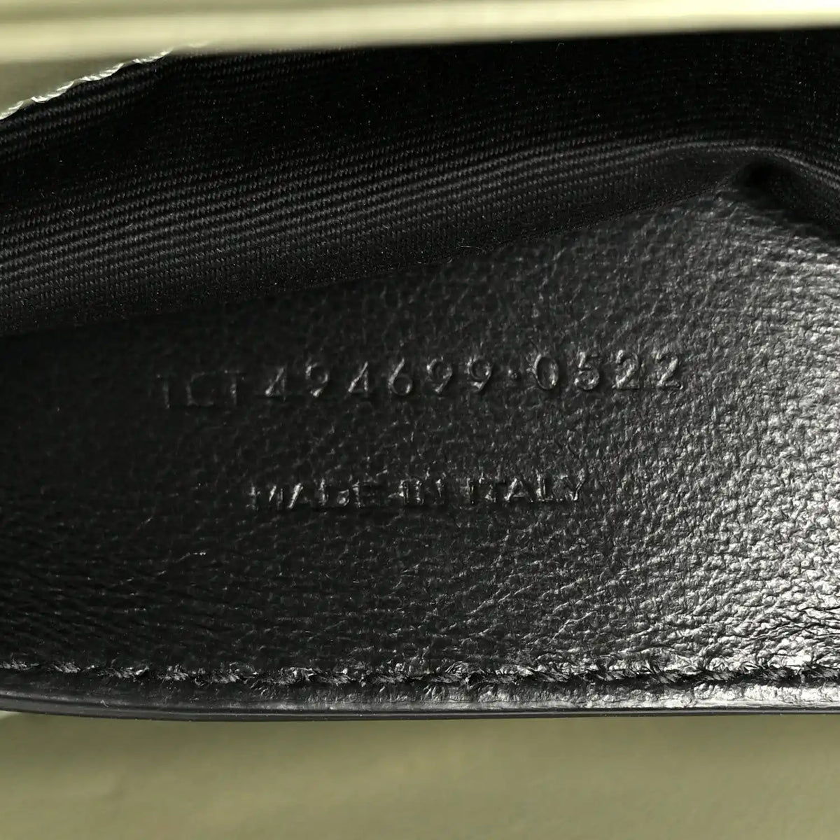Light sage leather interior base with stamped serial text near zipper opening