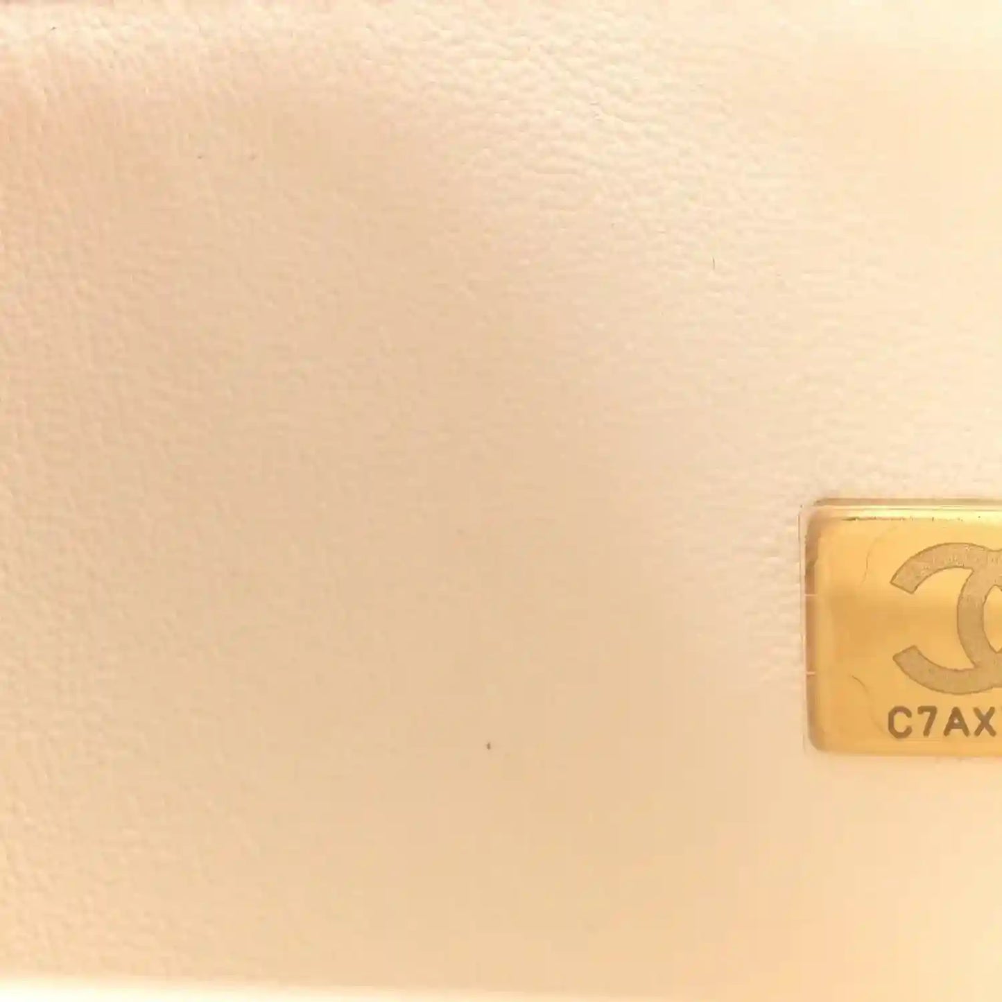White quilted leather bag corner with gold-tone hardware plaque