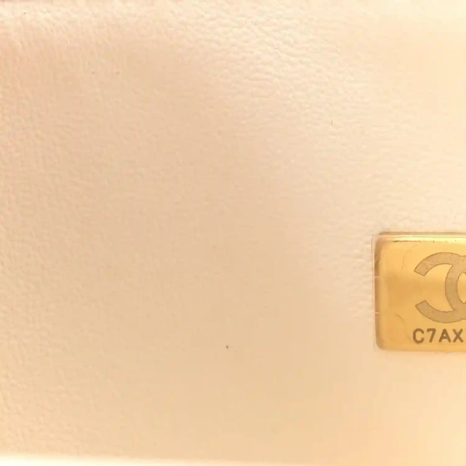 White quilted leather bag corner with gold-tone hardware plaque
